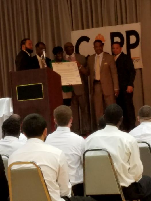 Graduates look on as leaders present the CAPP certificate on stage